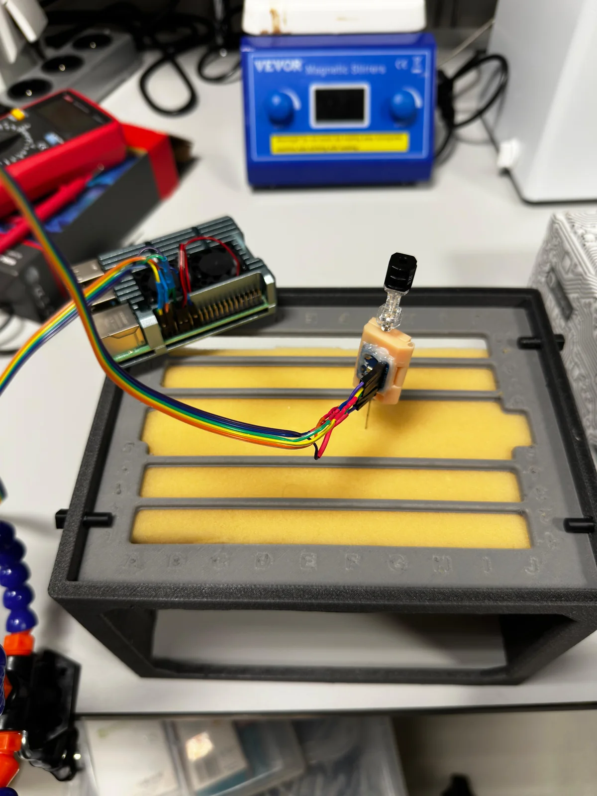 Needle-mounted vibroacoustic sensor positioned above a controlled material experiment